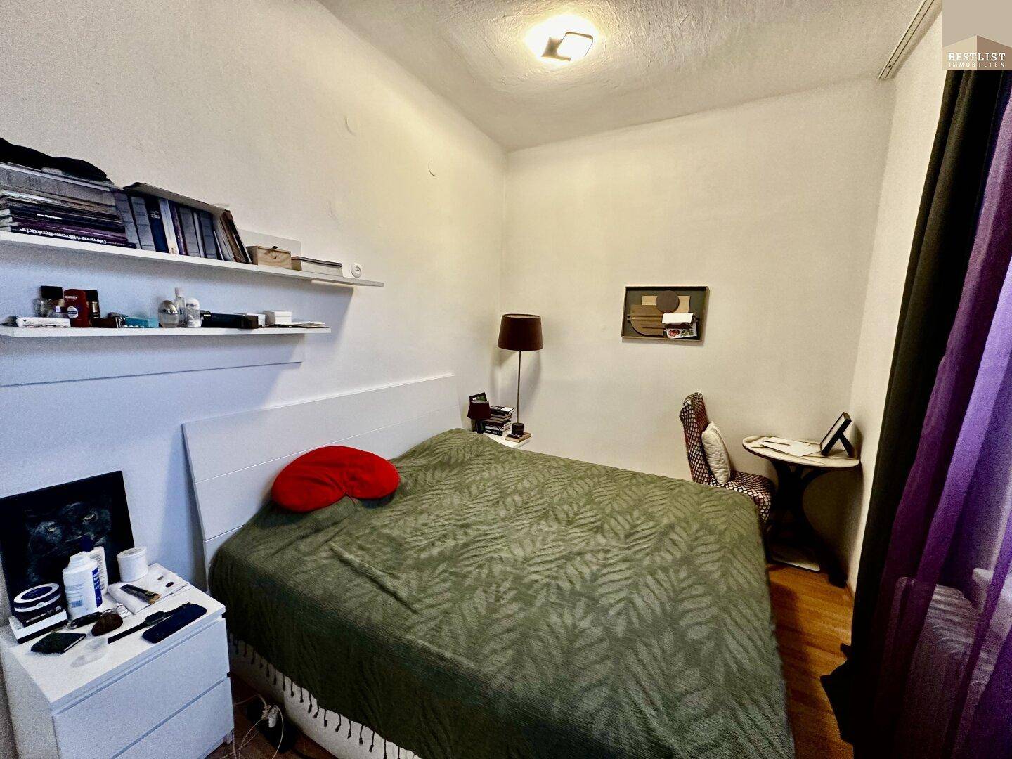 Schlafzimmer mit Doppelbett, Nachttisch und Regal, in ruhiger Atmosphäre mit Holzboden.