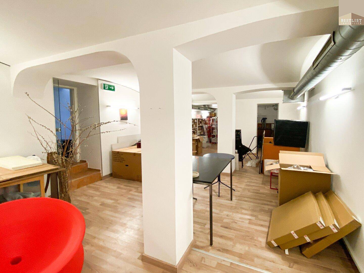 Geräumiger Kellerraum mit Holzboden, Säulen und Lagerkartons.