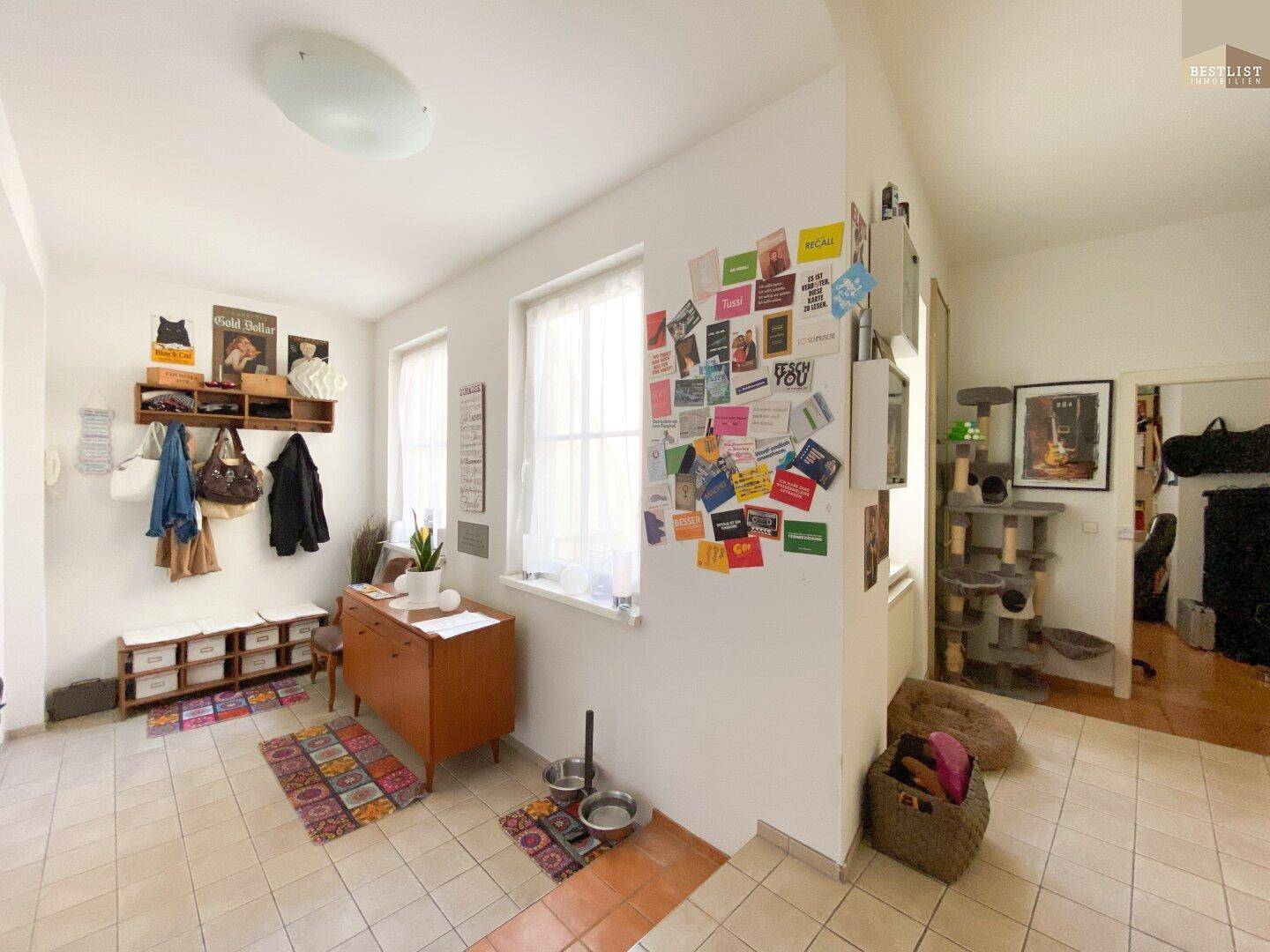 Heller Flur mit Fliesenboden, Garderobe und dekorativen Elementen.