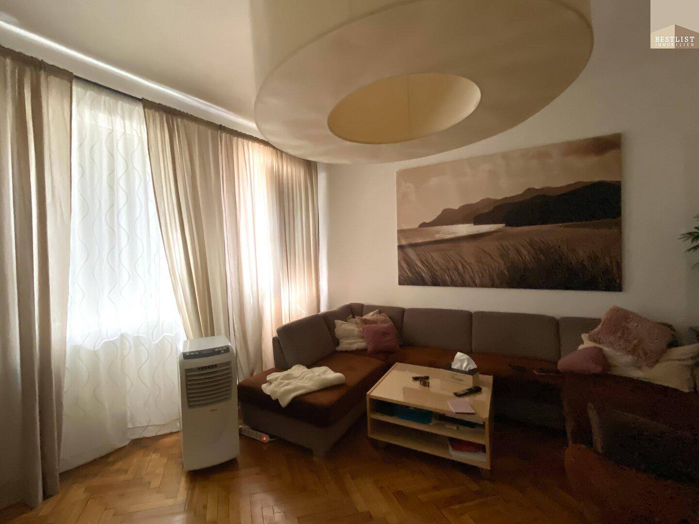 Helles Wohnzimmer mit Parkettboden, bequemer Sitzecke und großem Wandbild.