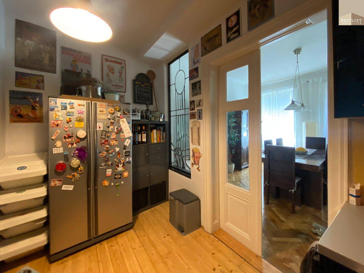 Küche mit Holzboden, großem Kühlschrank und Zugang zum Esszimmer.