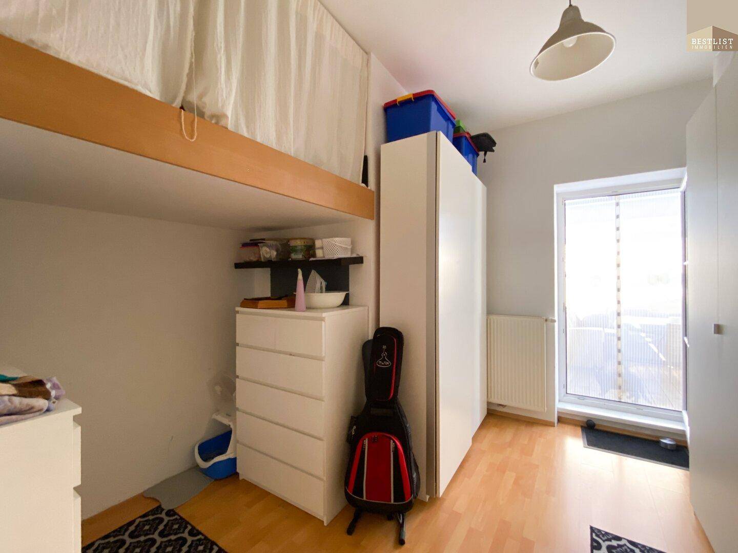 Schlafzimmer mit Hochbett, Kleiderschrank und Zugang zum Balkon.