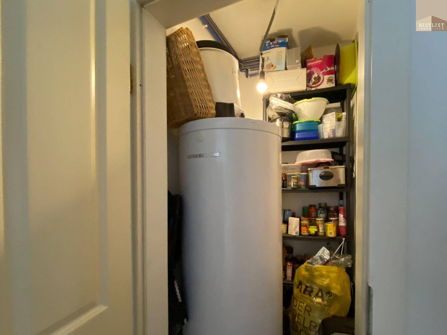 Abstellraum mit Warmwasserboiler und Regalen für Vorräte.