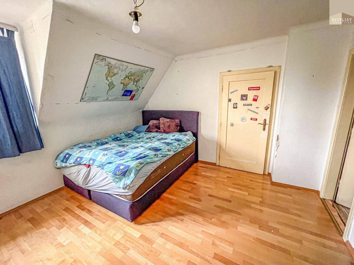 Schlafzimmer im Dachgeschoss mit Holzboden, schräger Decke und einem Bett.