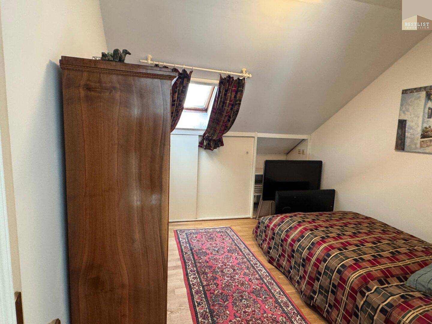 Gemütliches Schlafzimmer im Dachgeschoss mit Holzboden, Dachfenster und Stauraum.