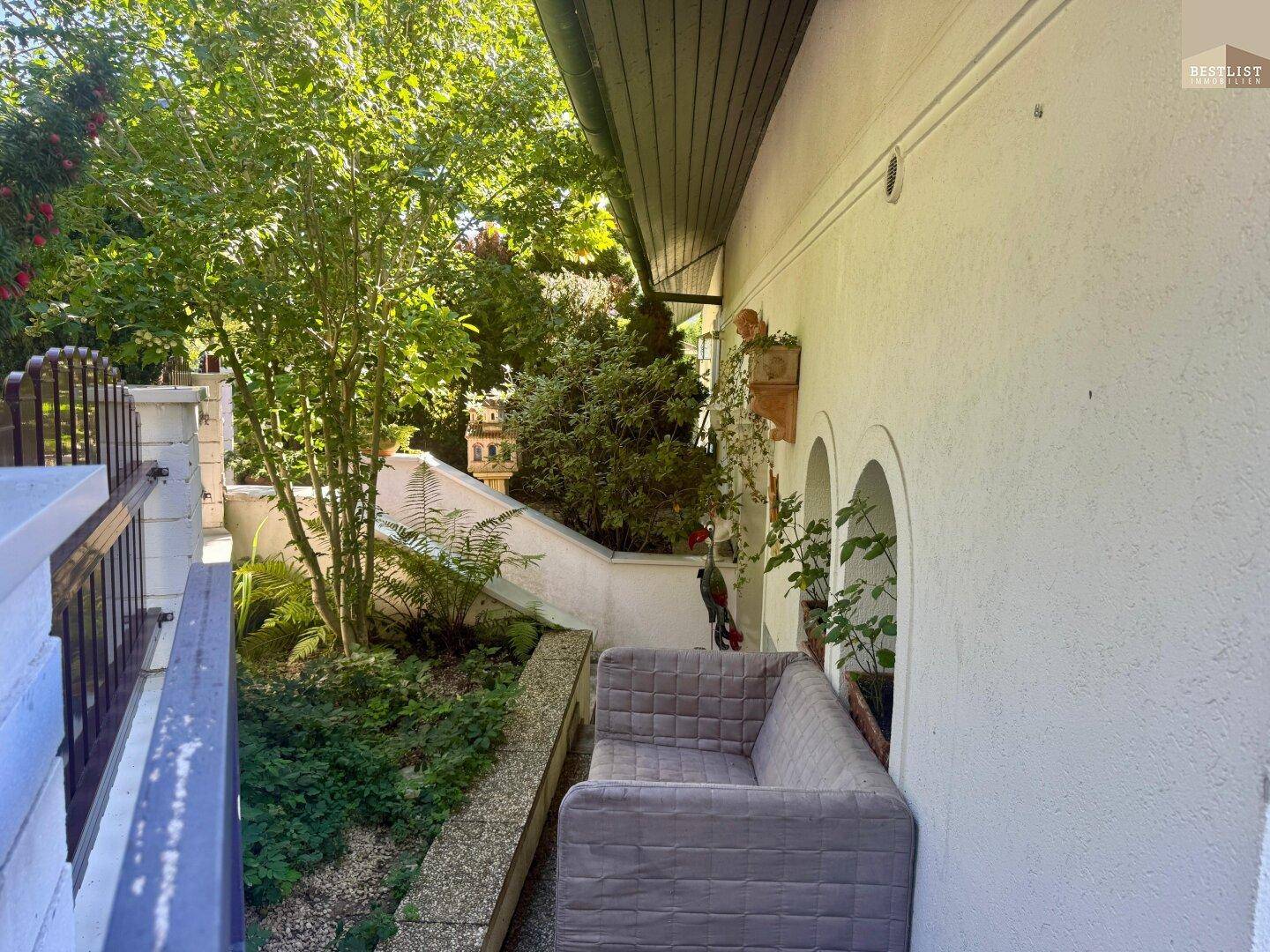 Kleiner, begrünter Balkon mit Sitzgelegenheit und Blick auf den Garten.