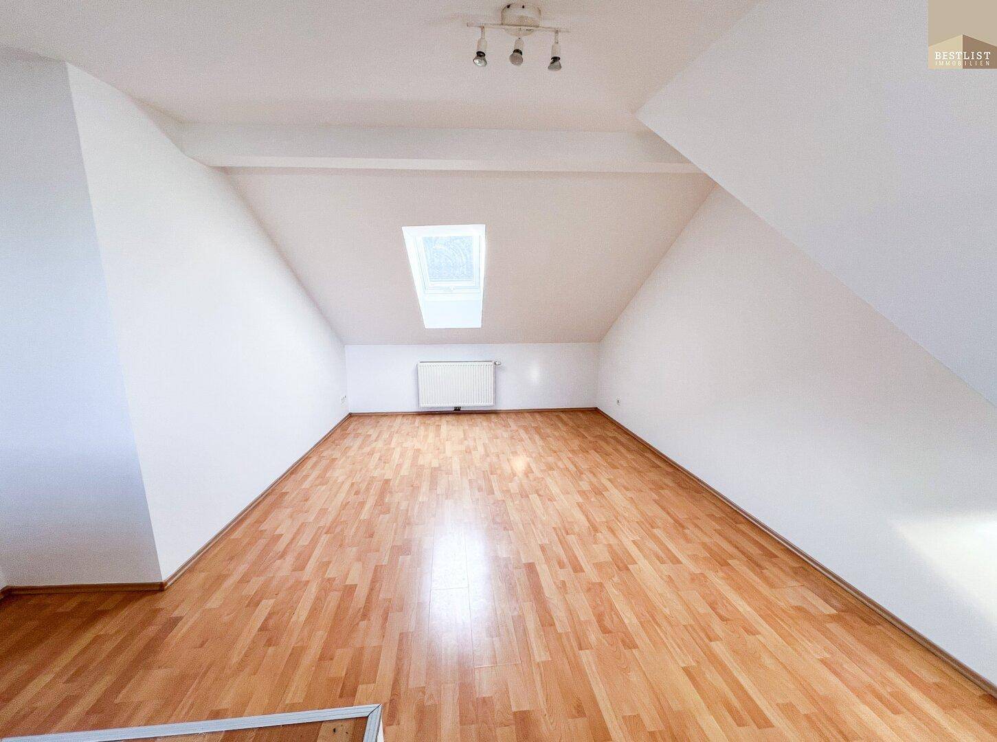 Geräumiger Dachbodenraum mit Laminatboden, Dachschräge und Dachfenster.