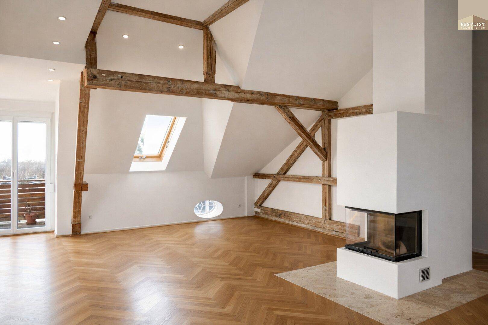 Geräumiges Wohnzimmer mit Kamin, Holzbalken, Fischgrätparkett und Zugang zum Balkon.