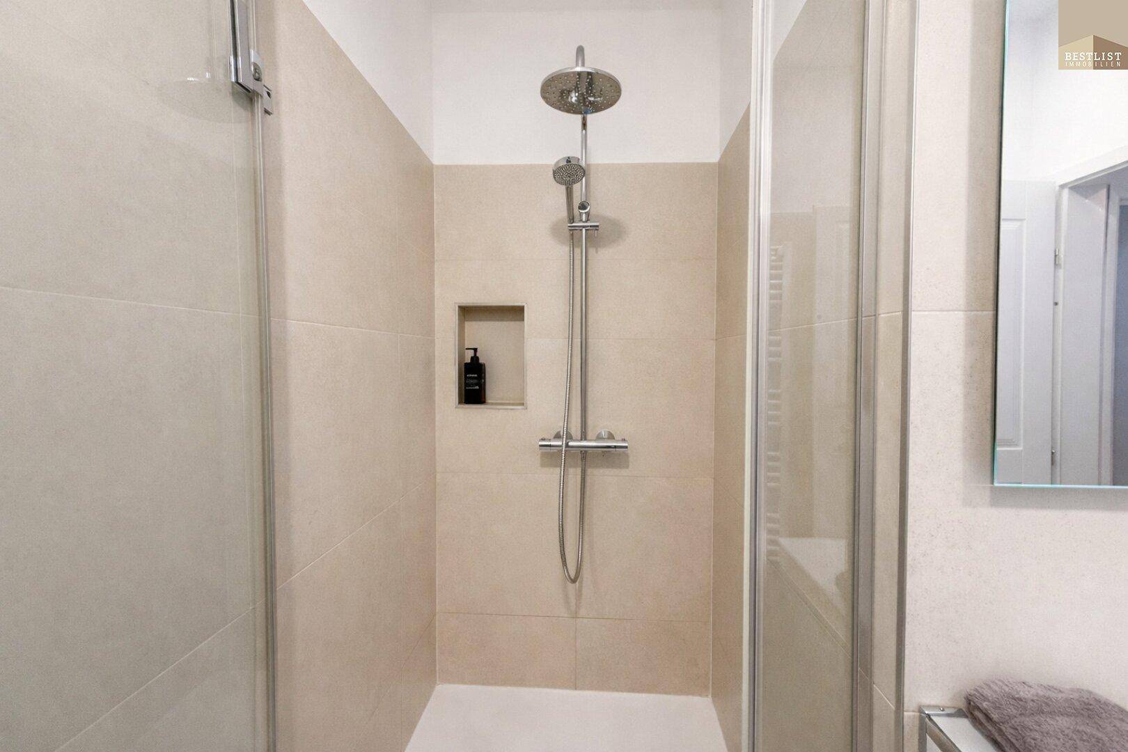 Moderne Duschkabine mit Regendusche und beigefarbenen Fliesen für ein entspannendes Duscherlebnis.