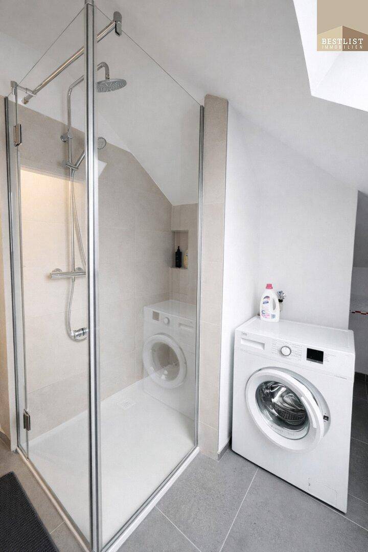 Modernes Badezimmer mit begehbarer Dusche und Waschmaschine unter der Dachschräge.