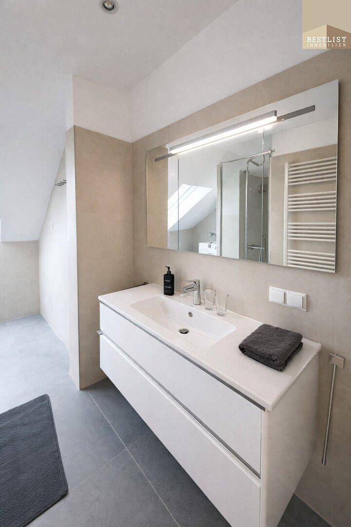 Modernes Badezimmer mit großem Waschtisch, Spiegel und beheiztem Handtuchhalter.