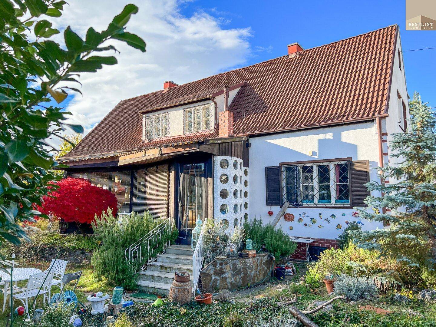 Charmantes Haus mit traditioneller Architektur, Fensterläden und einem gepflegten Vorgarten.