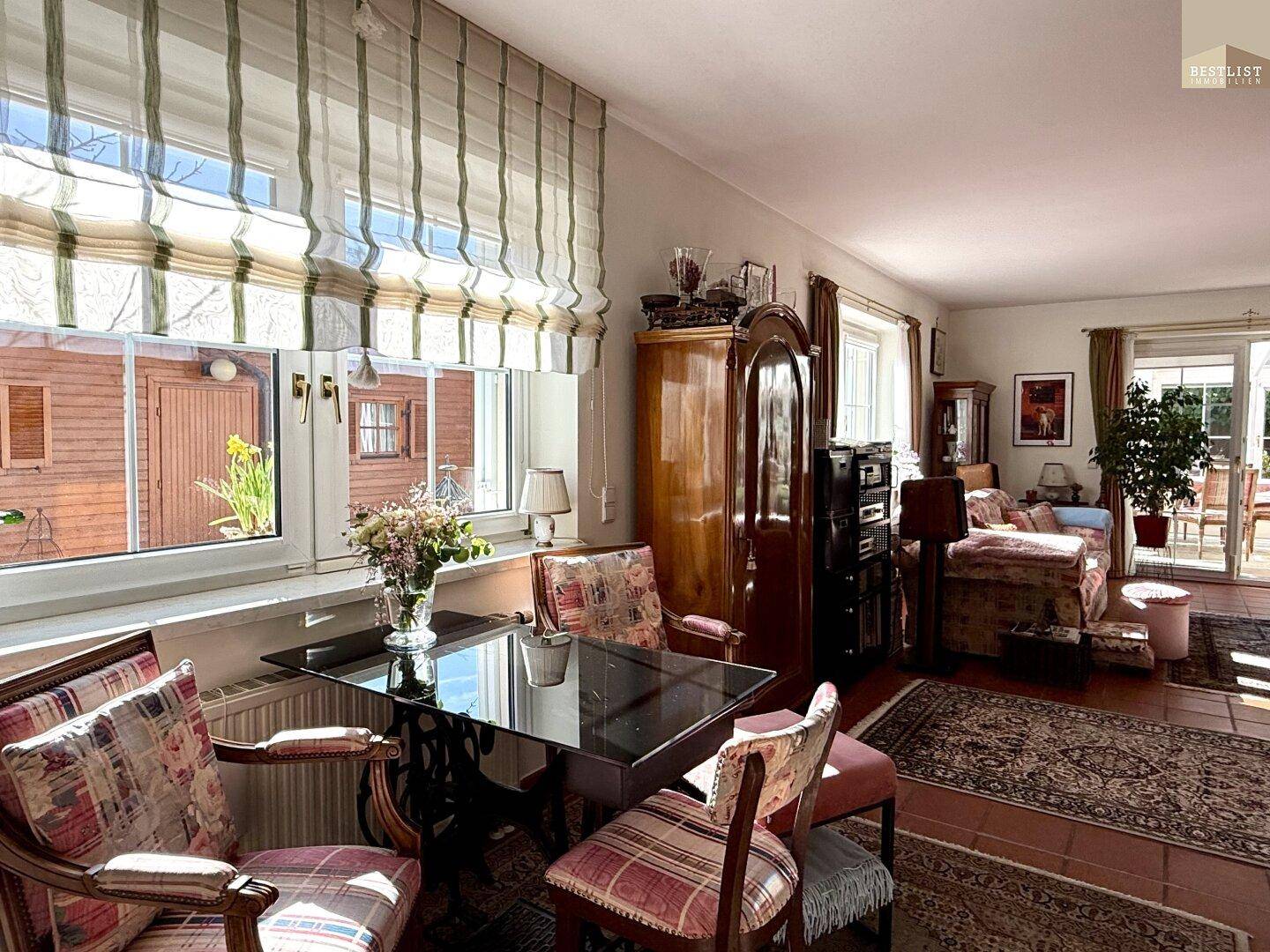 Heller Wohnbereich mit Esstisch, Terrakottafliesen und Blick in den Garten durch große Fenster.