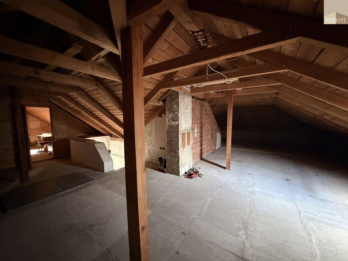Geräumiger Dachboden mit Holzbalken und ungenutzter Fläche für zukünftigen Ausbau.