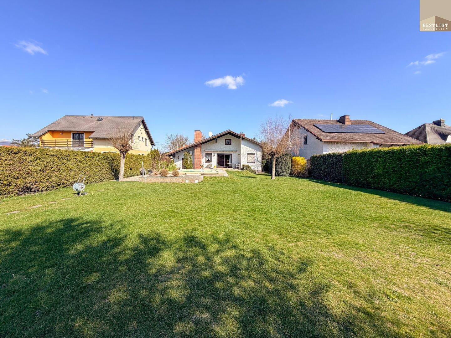 Großer, gepflegter Garten mit Rasenfläche, Hecken und Blick auf das Haus.