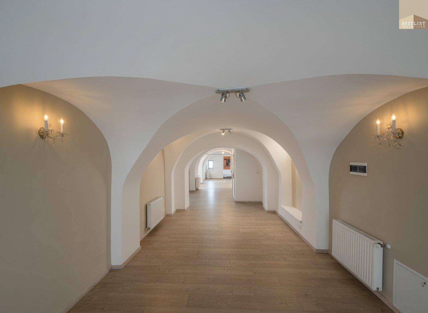 Langer Flur mit beeindruckenden Gewölbedecken und hellem Holzfußboden.
