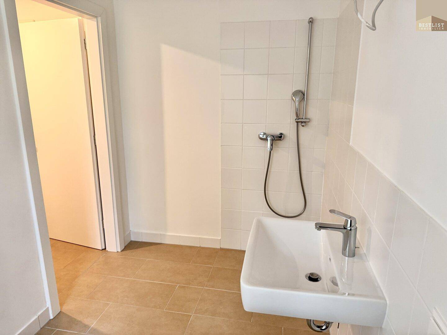 Modernes Badezimmer mit Duschbereich, Waschbecken und hellen Fliesen.