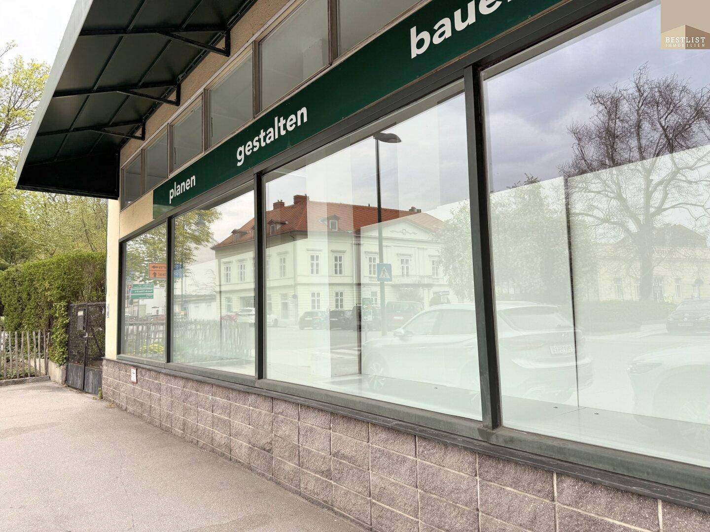 Außenansicht eines Geschäftsgebäudes mit großen Schaufenstern und Blick auf die Straße.
