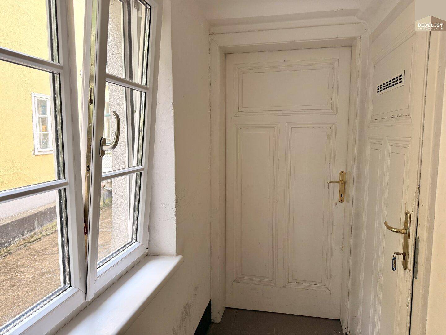 Heller Flur mit Fenster und zwei weißen Türen, die zu weiteren Räumen führen.