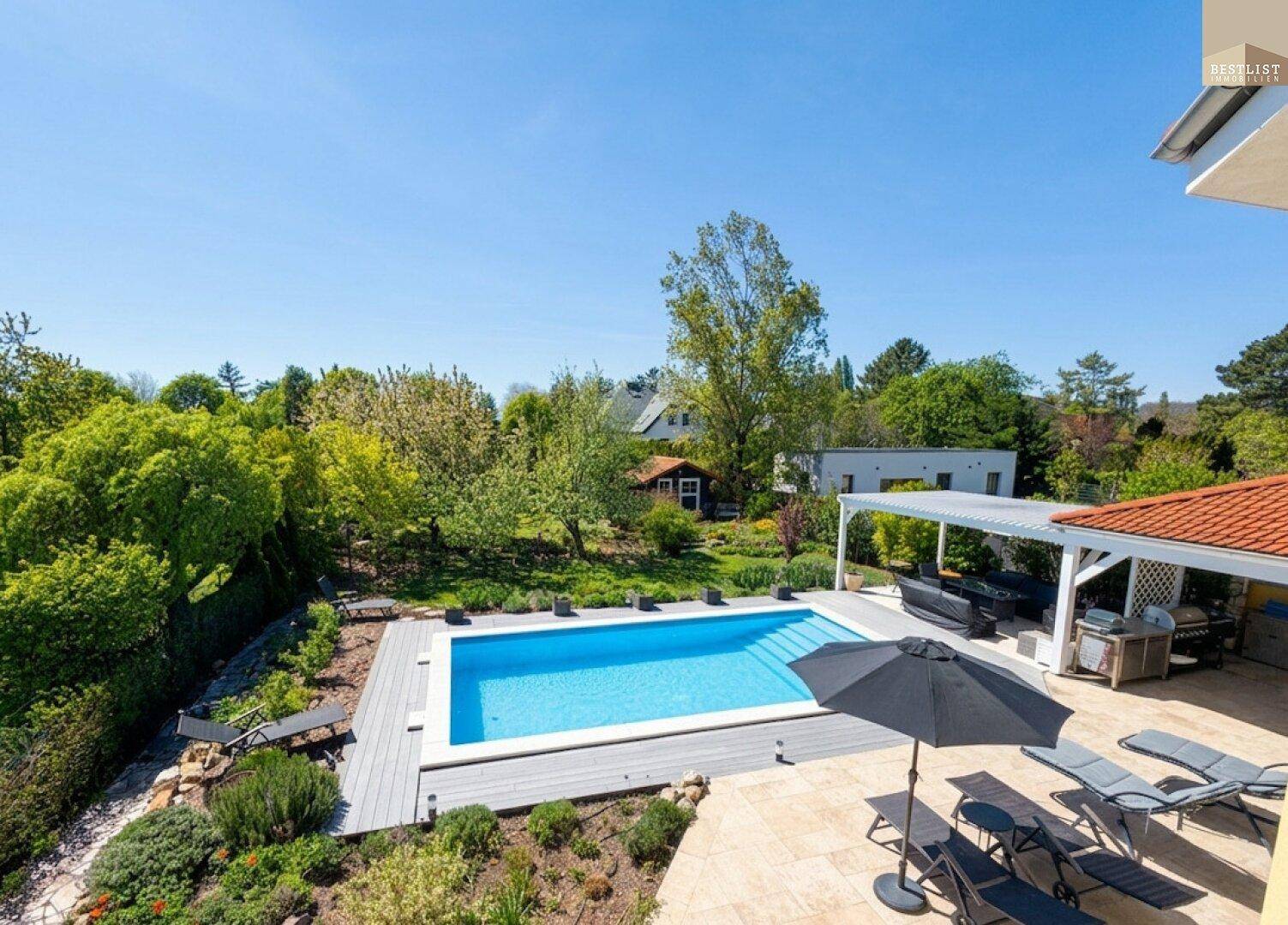 Große Sonnenterrasse mit Pool, Liegestühlen und Blick auf den weitläufigen Garten.