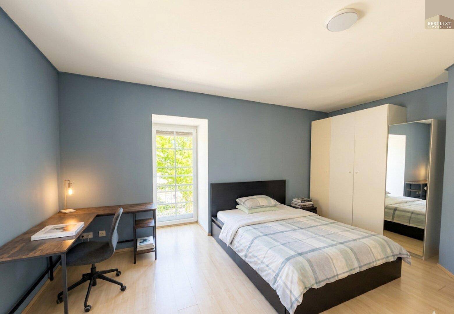 Jugendzimmer mit Einzelbett, Schreibtisch und Kleiderschrank, in Blautönen gehalten.