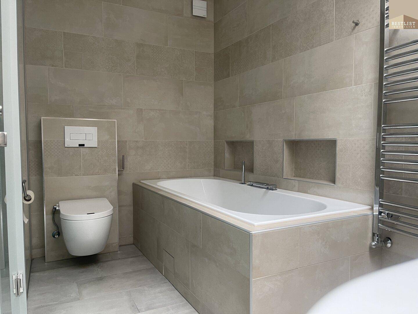 Modernes Badezimmer mit Badewanne, wandhängendem WC und beigefarbenen Fliesen.