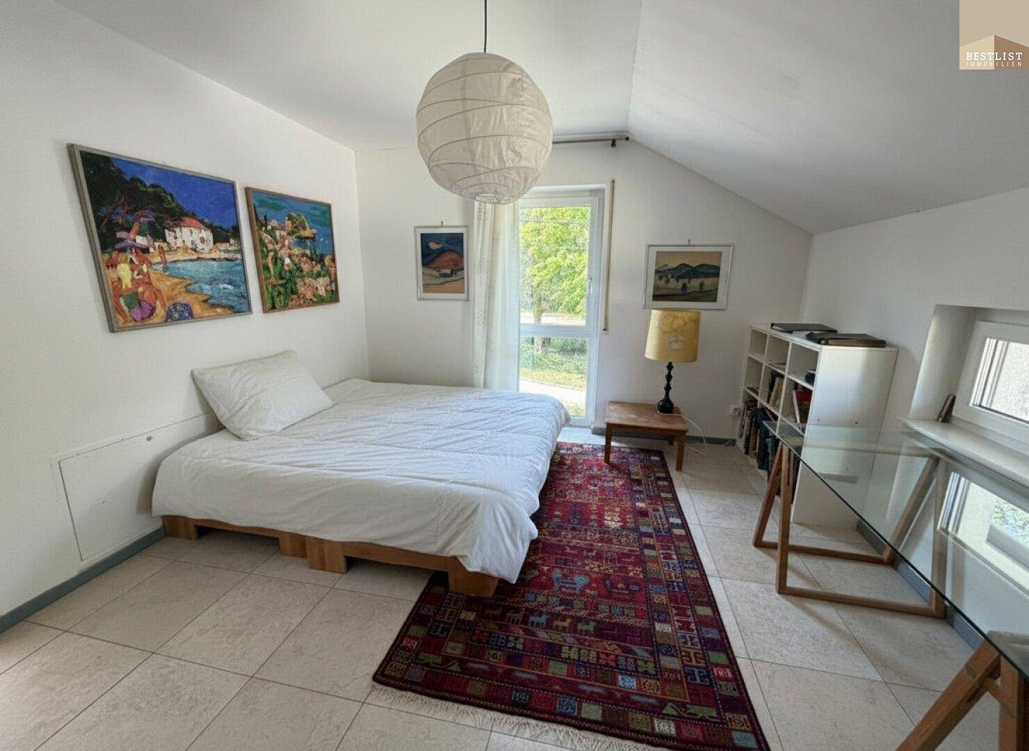 Gemütliches Schlafzimmer mit Einzelbett, Teppich und Blick ins Grüne.