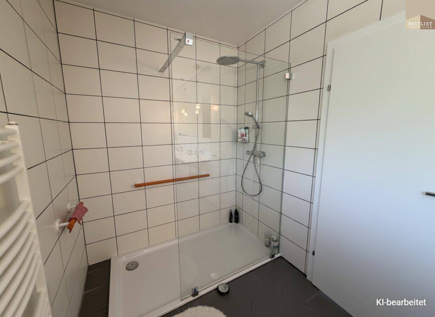 Große, moderne Dusche mit Glasabtrennung und weißen Fliesen im Badezimmer.