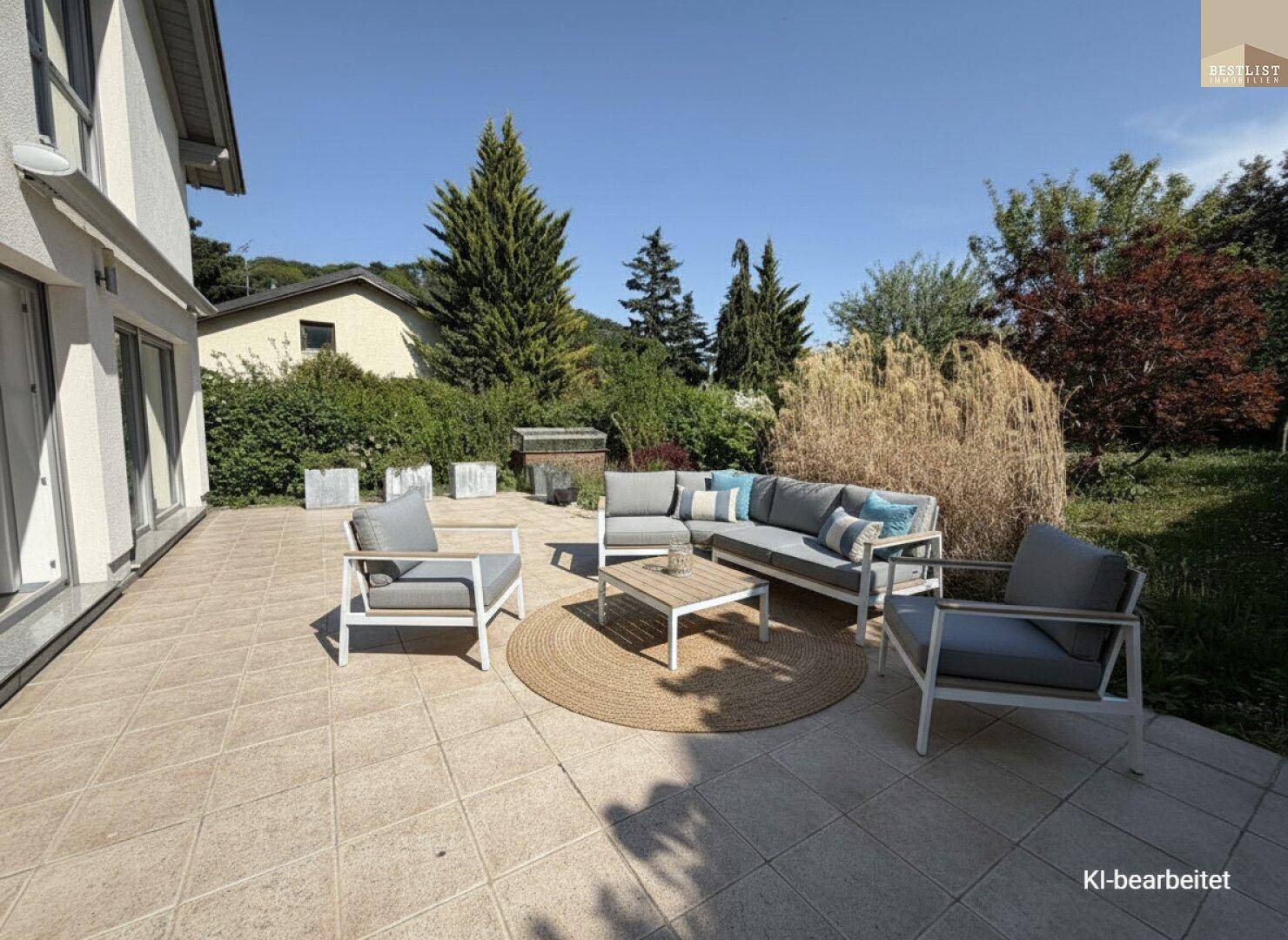 Große, geflieste Terrasse mit moderner Lounge-Möblierung und Blick ins Grüne.