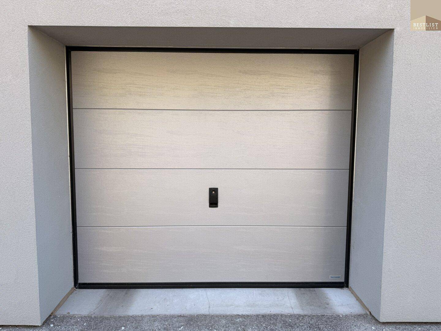 Moderne Garagentür in hellem Holzdesign, passend zur Fassade des Gebäudes.