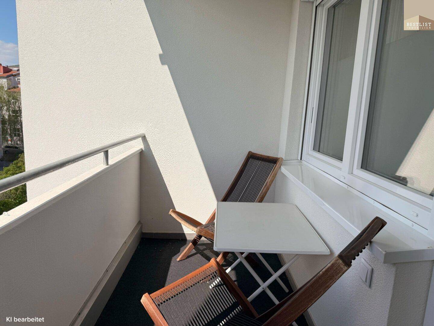 Kleiner Balkon mit zwei Stühlen und einem Tisch, ideal für entspannte Stunden im Freien.