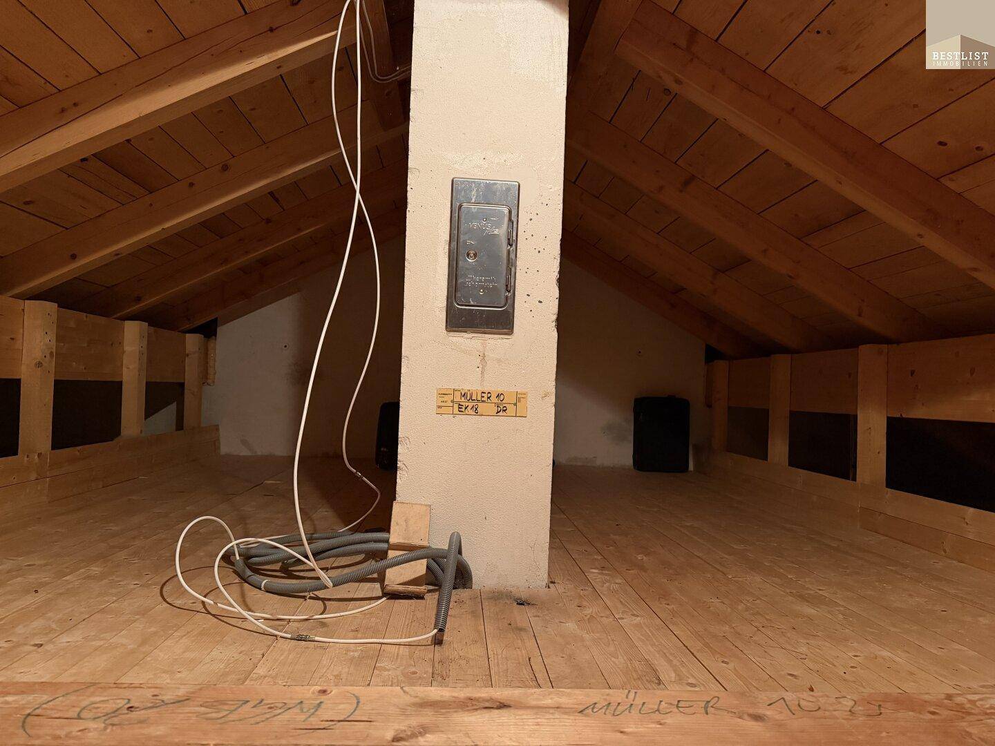 Unfertiger Dachboden mit sichtbaren Holzbalken, Holzdielenboden und schräger Dachkonstruktion.