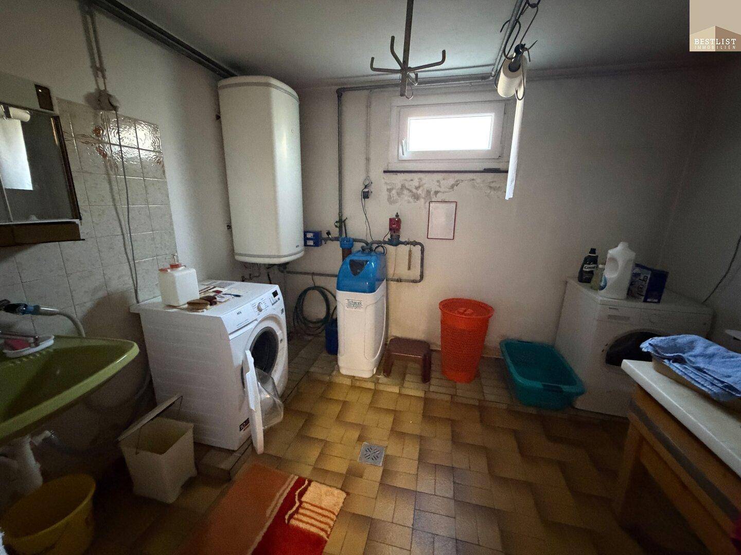 Waschküche im Keller mit Waschmaschine, Trockner und Wasserenthärtungsanlage für den Haushalt.