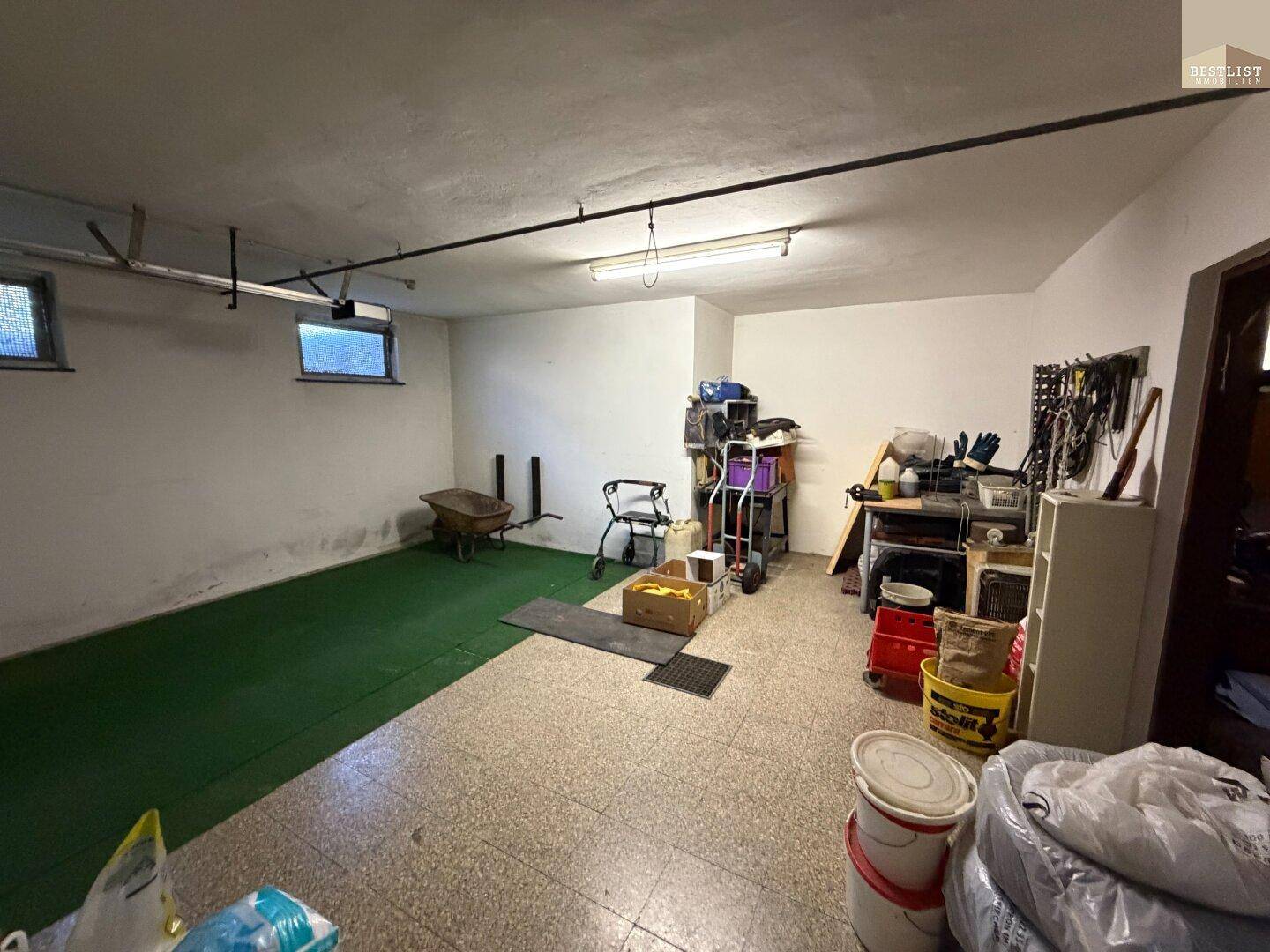 Großer Garagenbereich mit viel Stauraum und Zugang zu weiteren Kellerräumen.