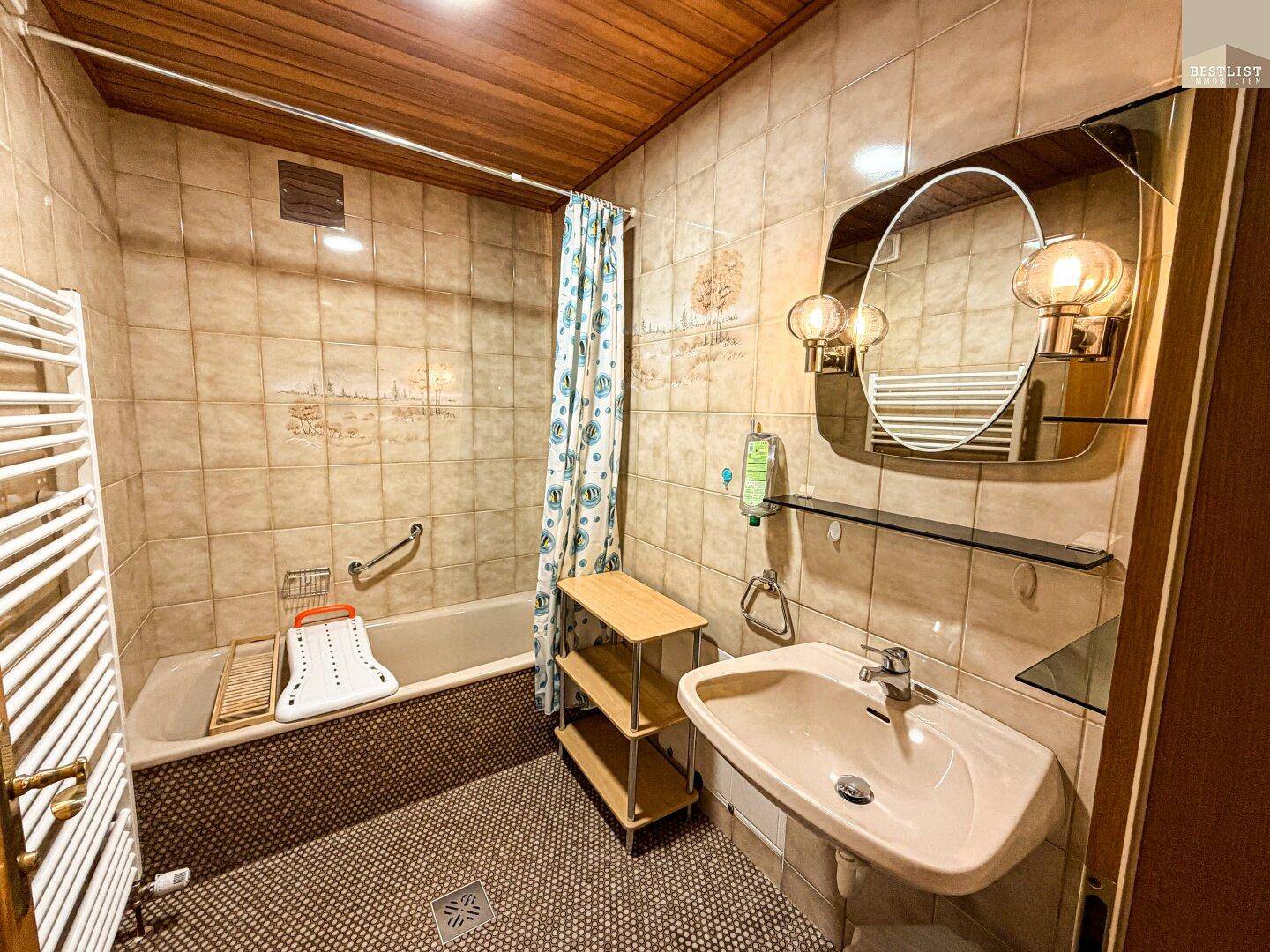 Badezimmer mit Badewanne, Waschbecken, Fliesen und beheiztem Handtuchhalter in traditionellem Stil.