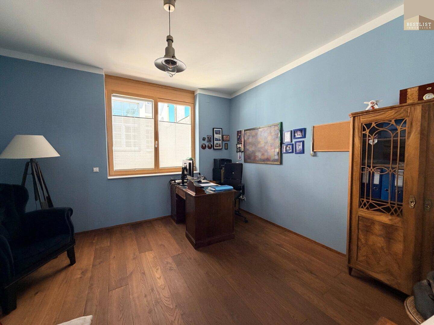 Ruhiges Arbeitszimmer mit Holzboden, blau gestrichenen Wänden und klassischem Schreibtisch.