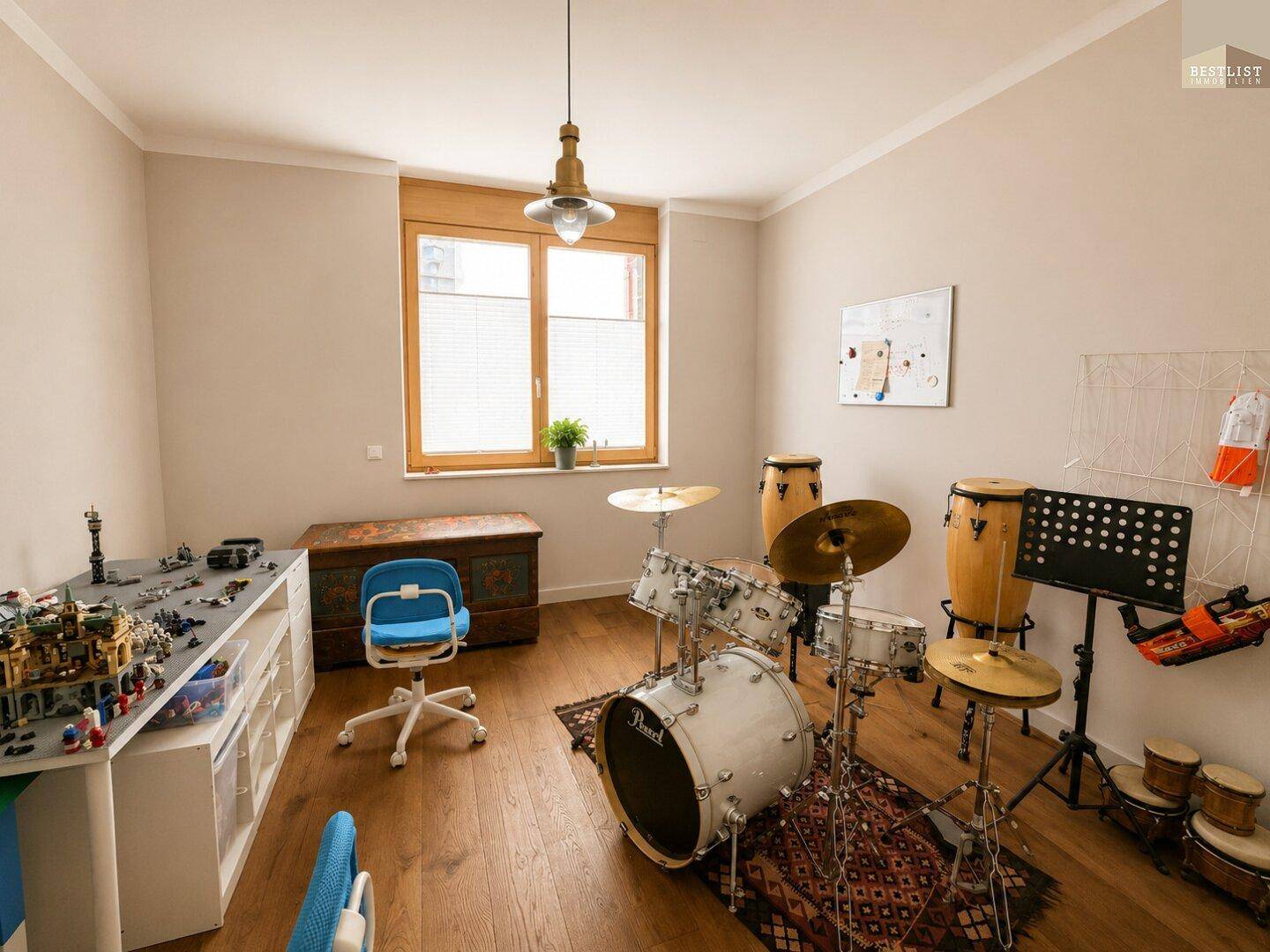 Geräumiges Zimmer mit Holzboden, Schlagzeug und Fenster, ideal für Hobbys.
