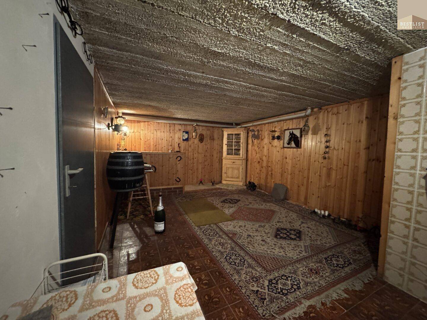 Rustikaler Kellerraum mit Holzvertäfelung, Teppich und dekorativen Elementen.