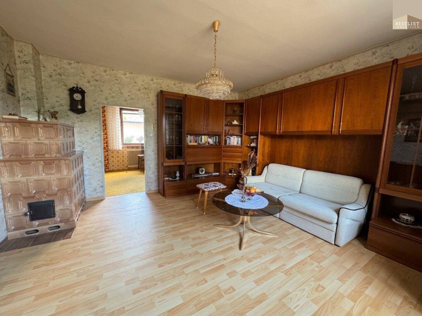 Gemütliches Wohnzimmer mit Kachelofen, Holzmöbeln und einem Sofa, das zum Entspannen einlädt.