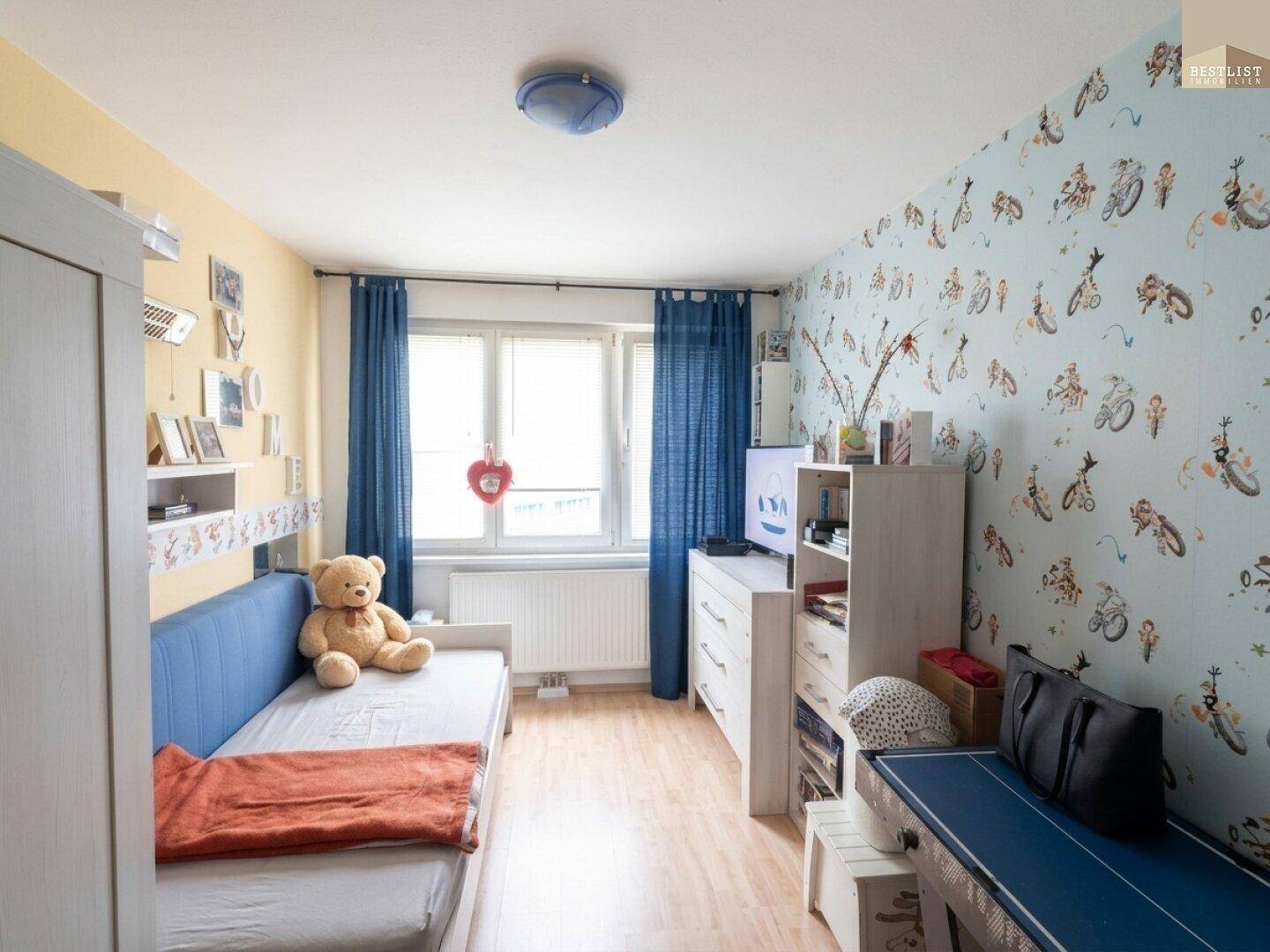Kinderzimmer mit farbenfroher Tapete, Einzelbett und Fenster für natürliches Licht.