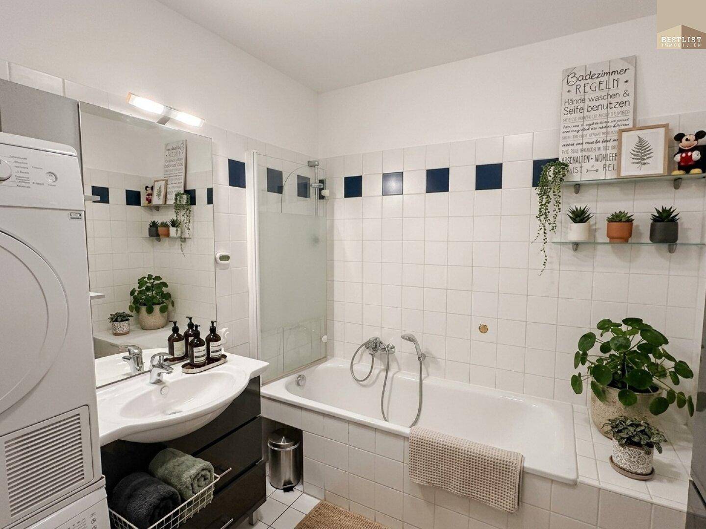 Badezimmer mit Badewanne, Dusche, Waschbecken und integrierter Waschmaschine.
