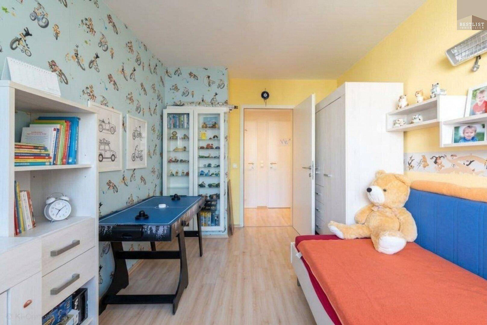 Kinderzimmer mit Spieltisch, farbenfroher Tapete und ausreichend Stauraum.