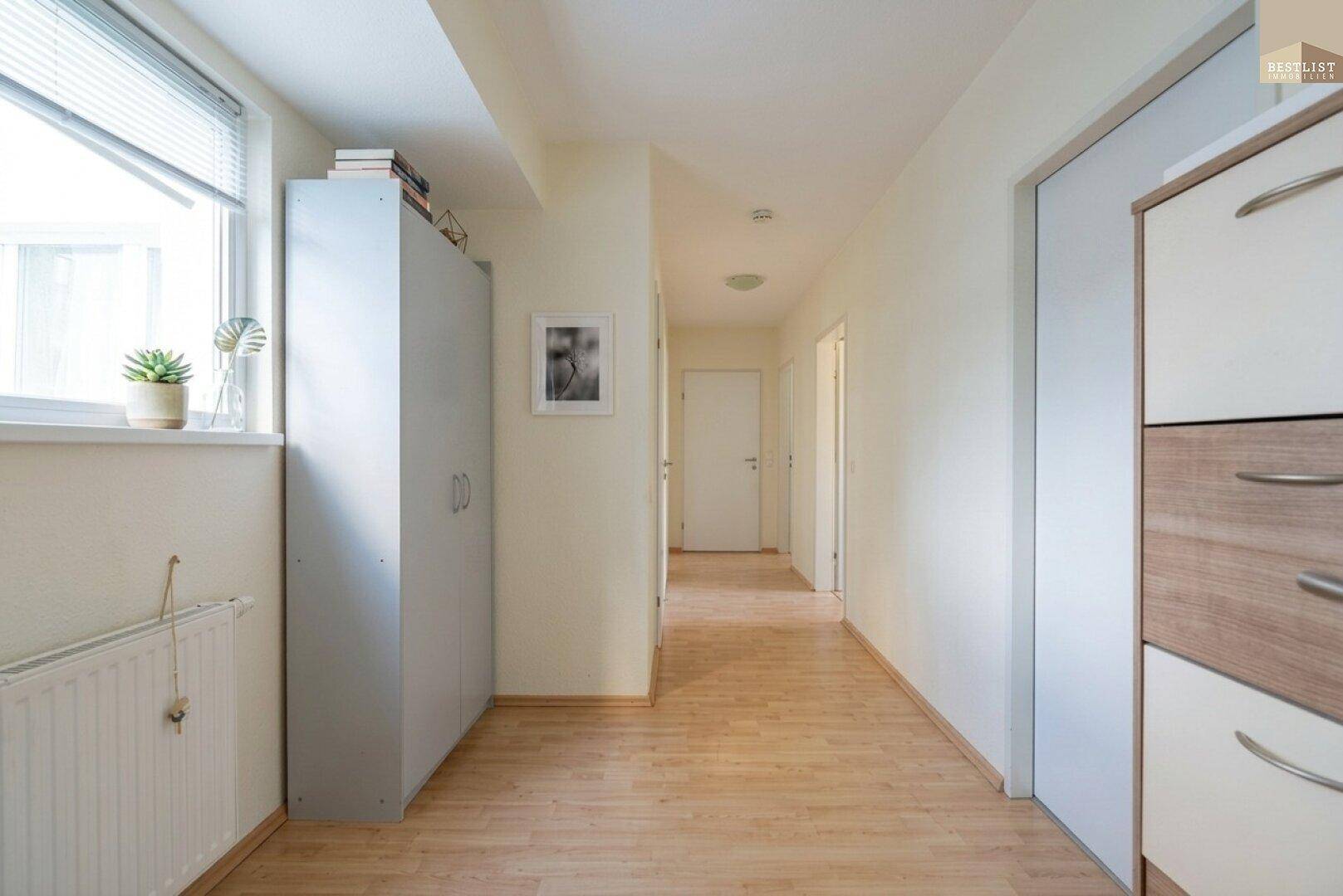 Langer Flur mit Laminatboden, Fenster und zusätzlichem Stauraum.