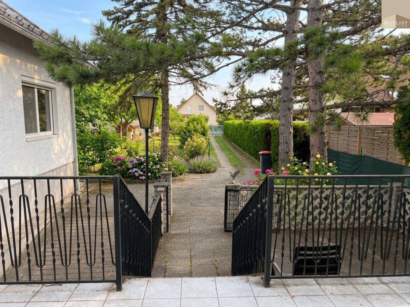 Gepflasterter Weg durch den Garten mit Laterne und Blick auf ein weiteres Gebäude.