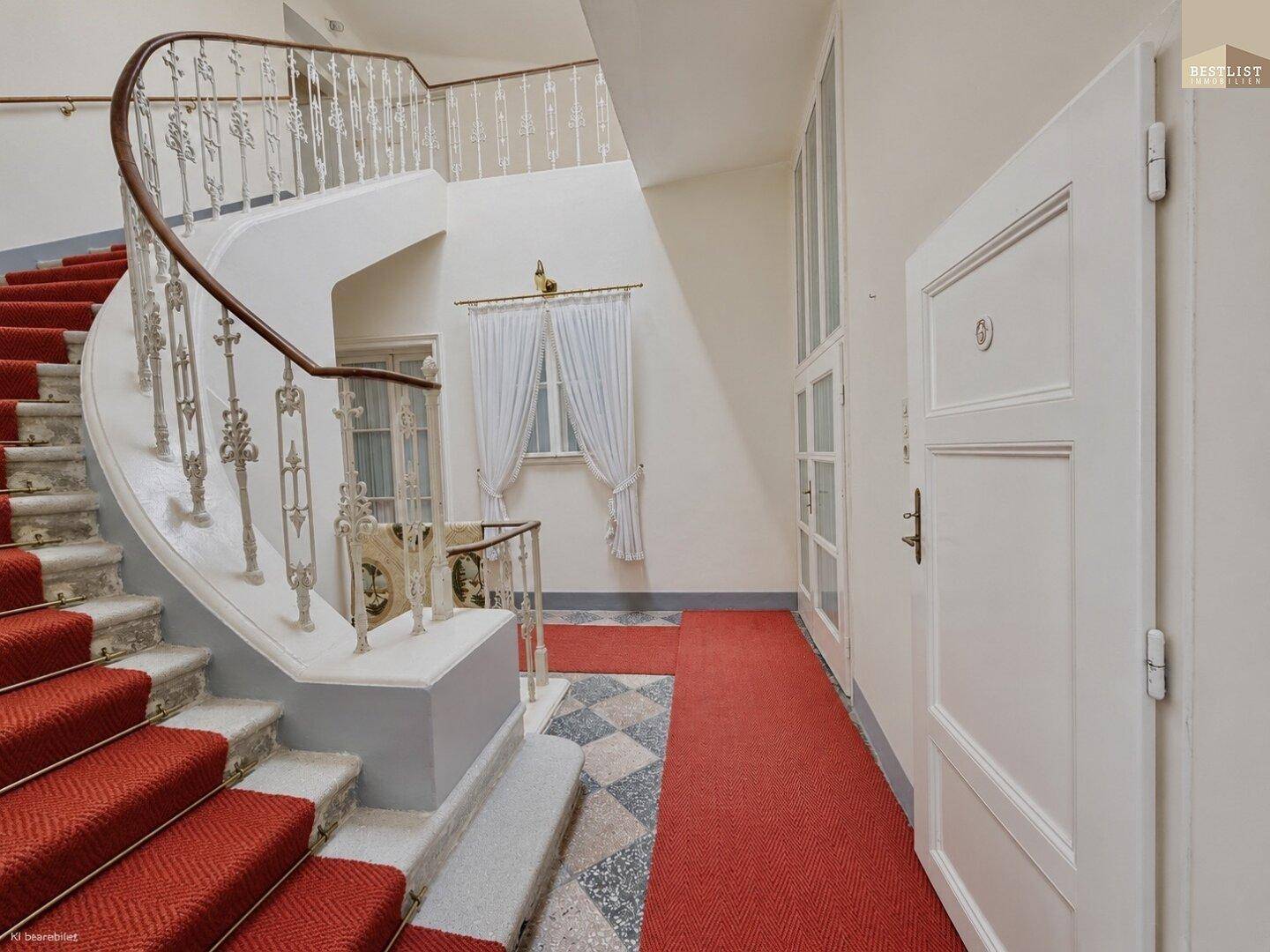 Elegantes Treppenhaus mit rotem Teppichläufer und geschwungenem Geländer in einem historischen Gebäude.