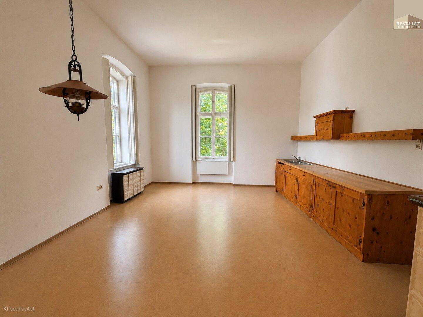 Einfache Küche mit langen Holzschränken, zwei Fenstern und einem schlichten Hängelampen-Design.