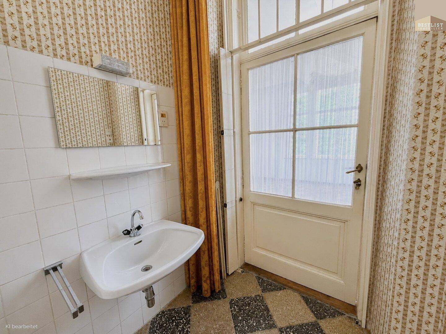 Kleines Badezimmer mit Waschbecken, Spiegel und einer undurchsichtigen Tür für Privatsphäre.