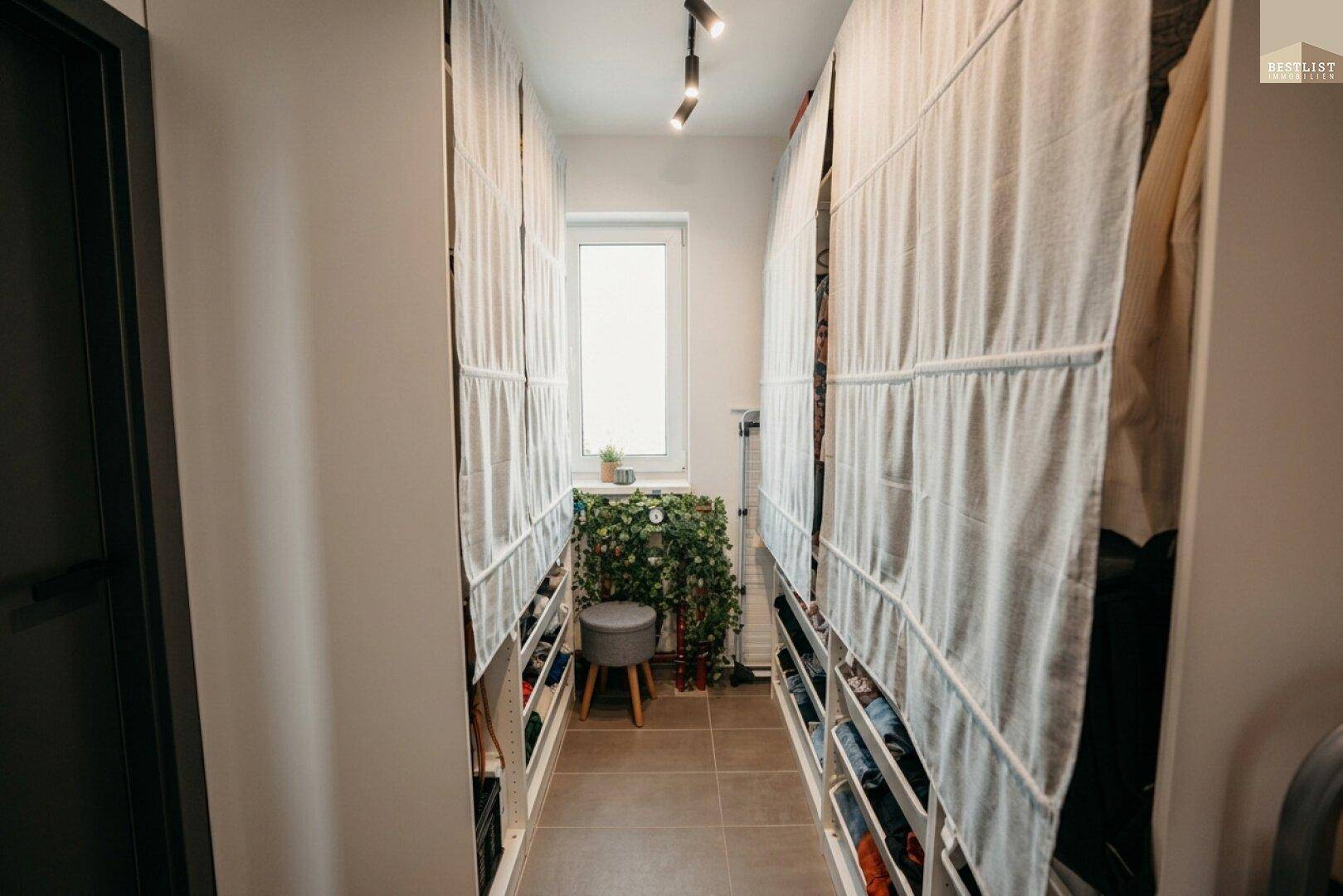 Praktischer begehbarer Kleiderschrank mit Regalen und Fenster für Tageslicht.