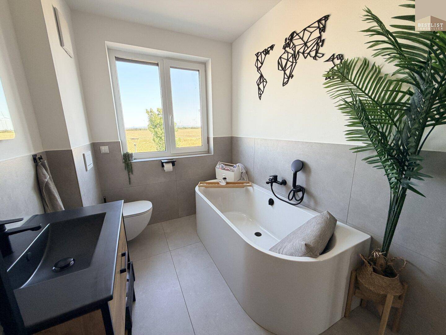 Geräumiges Badezimmer mit moderner Badewanne, Fenster und stilvoller Dekoration.