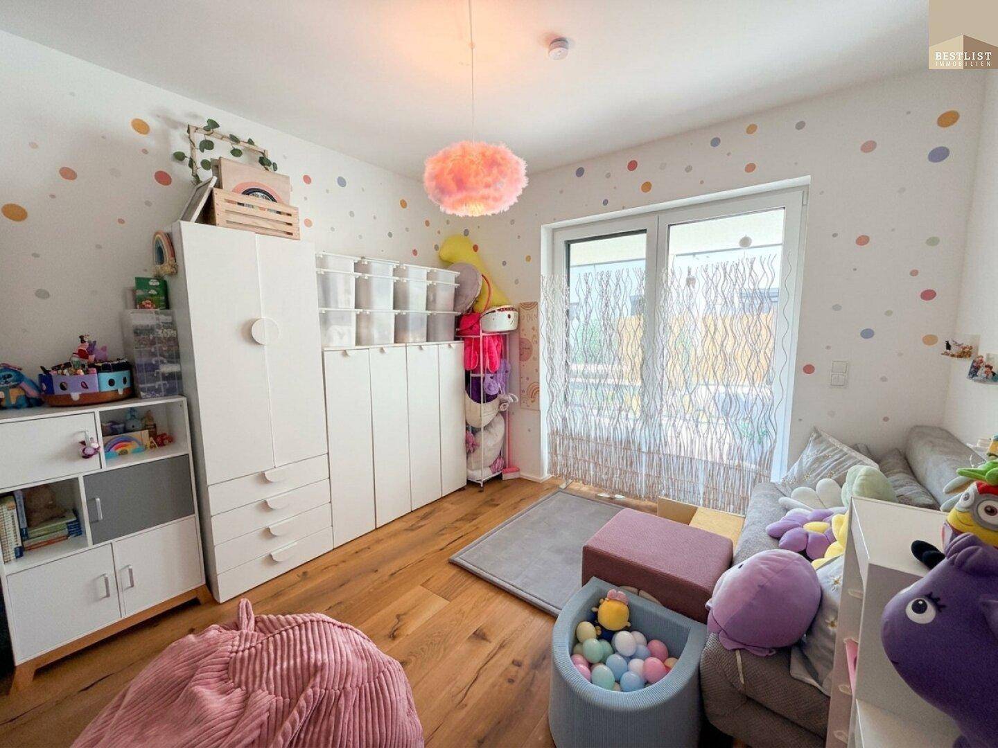 Farbenfrohes Kinderzimmer mit Holzboden, Spielzeug und Zugang zum Außenbereich.